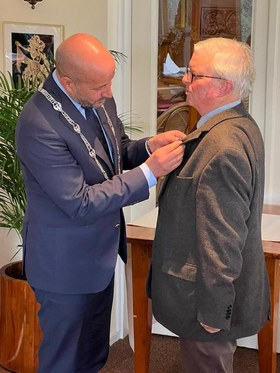 Burgemeester Ahmed Marcouch spelt de onderscheiding op de borst bij Gijs Schut