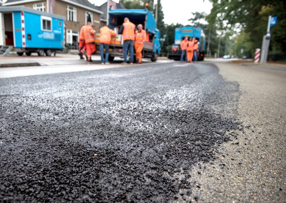 Wegwerkers voeren asfalteerwerkzaamheden uit