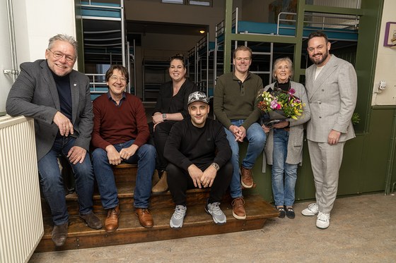 Een aantal genomineerden voor de Arnhemse Stadsprijs voor Vrijwilligerswerk poseren met wethouder Mark Lauriks bij opvangbedden.