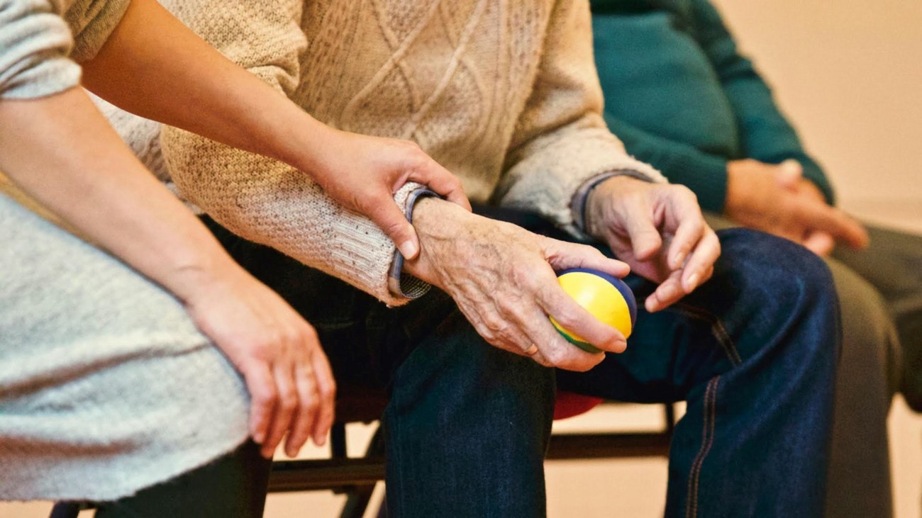 Vrouw legt hand op arm van persoon met dementie