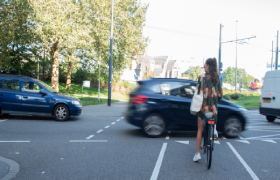 Fietser wachtend voor een drukke weg