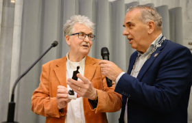 Schrijver Theo brink (links) krijgt een Arnhems Meisje van wethouder Bob Roelofs (rechts)