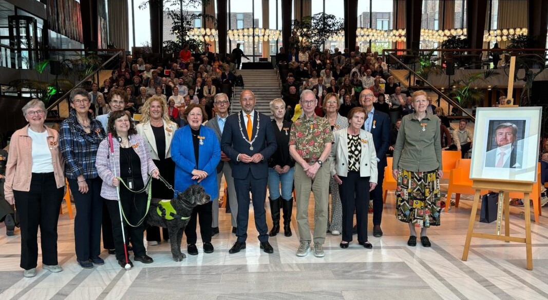Groepsfoto van de 13 gedecoreerden samen met burgemeester Ahmed Marcouch (in het midden)