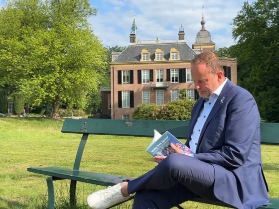 Wethouder Maurits van de Geijn leest op een bankje in een park het boek 'Volg het Spoor'.
