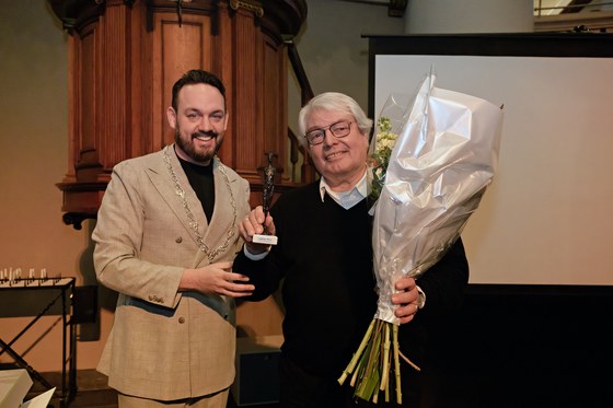 Locoburgemeester Mark Lauriks (links) en Rudolf Beijerman (rechts) met een bos bloemen in zijn handen. Rudolf heeft ook het Arnhems Meisje in zijn hand.