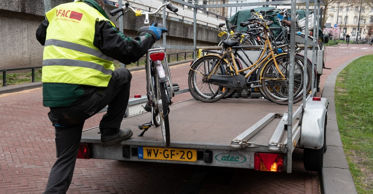 Een medewerker van AFAC ruimt fout geparkeerde fietsen op en plaatst ze in een aanhangwagen om ze mee te nemen