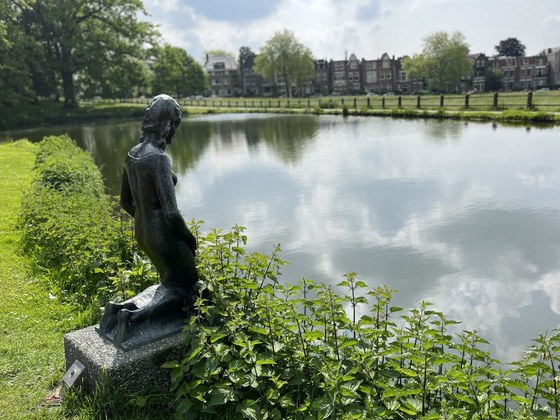 Een vijver in Park Sonsbeek. Links in beeld staat een standbeeld van een persoon knielend naast de vijver.