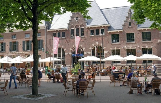 Een café in Arnhem met een vol terras ervoor.