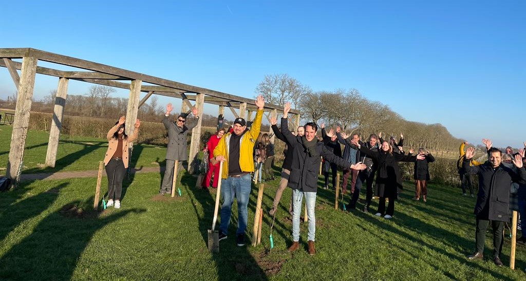 Wethouder Paul Smeulders (zwarte jas, midden) met nieuwkomers en juichen met hun handen omhoog