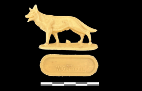 Een geel plastic dierfiguurtje van een wolf of Duitse herder uit de Koude Oorlog