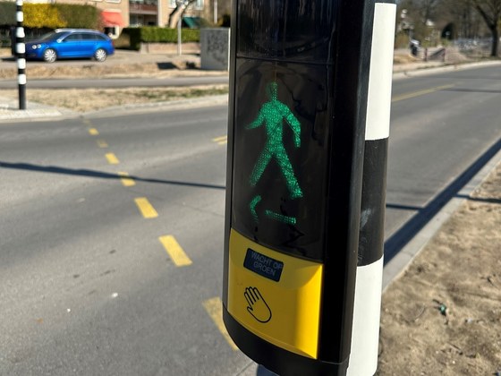 Het nieuwe verkeerslicht. Boven de drukknop op de paal zie je een groen oversteekteken.