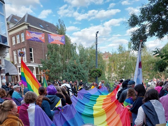 Mensen dragen de regenboogvlag door de binnenstad van Arnhem.