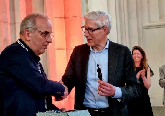 Loco-burgemeester Bob Roelofs (link in beeld) overhandigt het beeldje van het Arnhems meisje aan Peter Ruigrok (rechts in beeld).