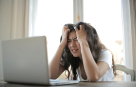 Een dame zit voor haar laptop met de handen in het haar