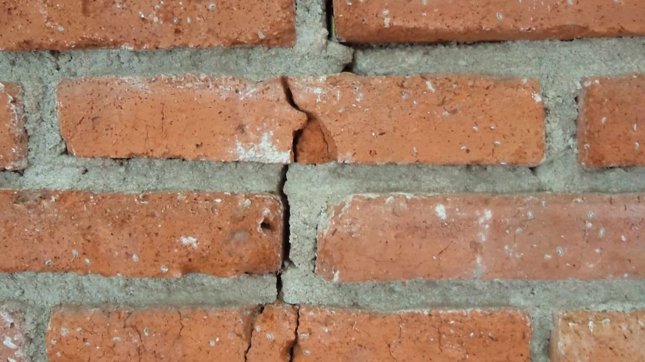 Een bakstenen muur met in het midden een scheur in de stenen.