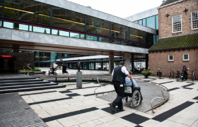 Een medewerker van de gemeente helpt een bezoeker in een rolstoel bij het betreden van het stadhuis